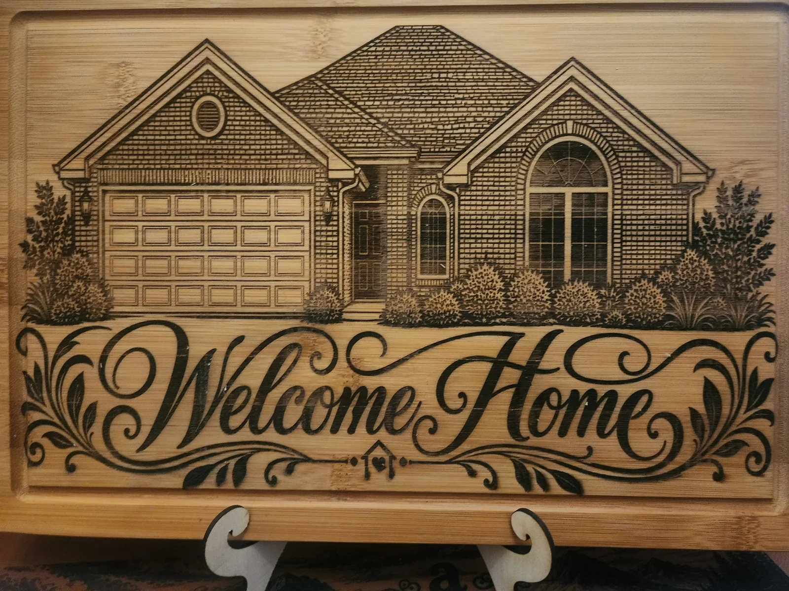 A wooden sign with a laser-engraved house illustration and the words 'Welcome Home' in cursive.