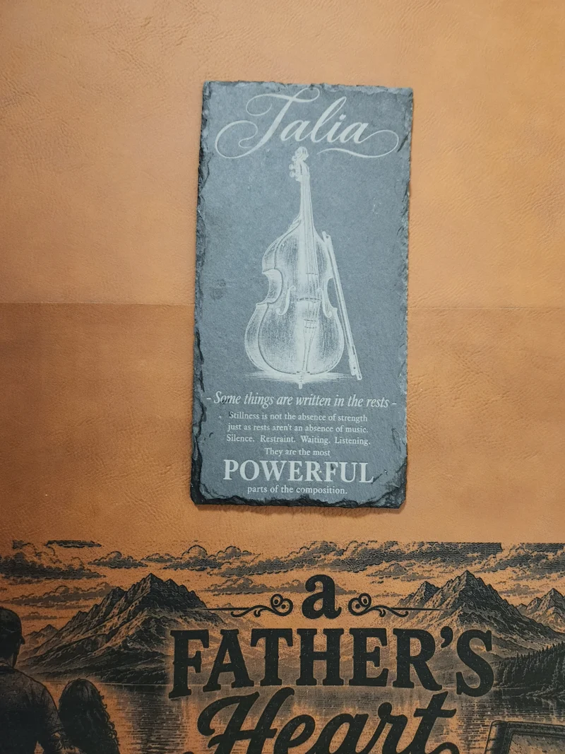 Engraved slate gift for a young musician named Talia, featuring a double bass and the words Some things are written in the rests, displayed above A Father's Heart artwork.