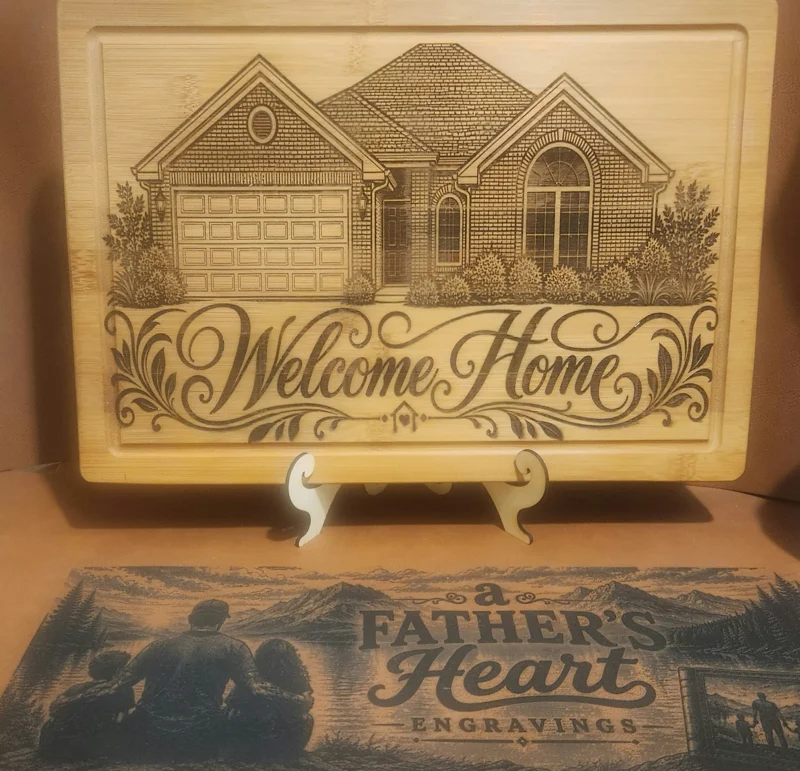 A laser-engraved wooden sign featuring a house illustration and the words 'Welcome Home,' with a smaller sign below reading 'a FATHER'S HEART ENGRAVINGS.'