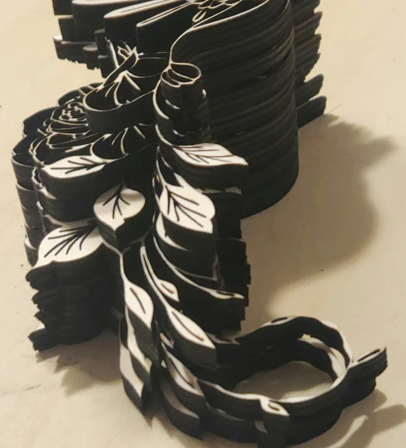 Layered laser-cut wooden artwork of a hummingbird flying beside a large rose with detailed leaves and flowers, created in memory of the artist's late mother and her love of hummingbirds Closeup of flowers